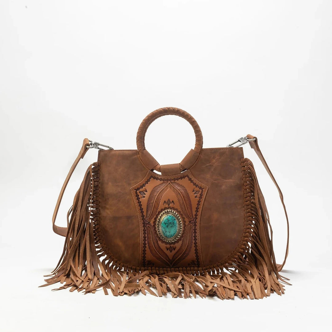 Brown leather handbag with fringe and turquoise stone on a white background