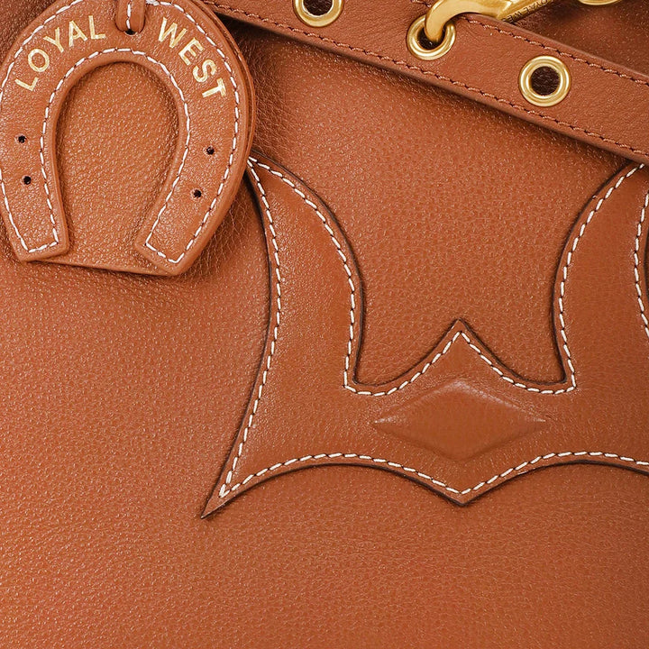 Close-up of a brown leather product with 'Loyal West' branding and horseshoe emblem.