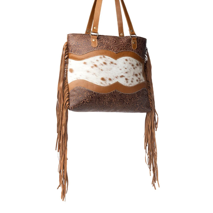 Brown leather handbag with cowhide and fringes on a white background